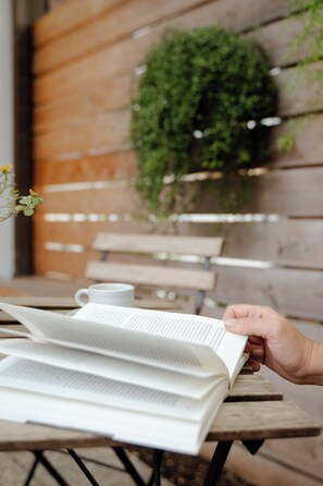 A person reading a book at a wooden table with a white mug and a plant in the background. - Bed and Bike Verona (Verona)
