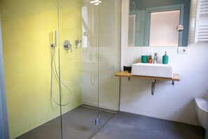 A bathroom with a glass shower enclosure, a white sink with a wooden shelf, and a mirror above the sink. - Bed and Bike Verona (Verona)