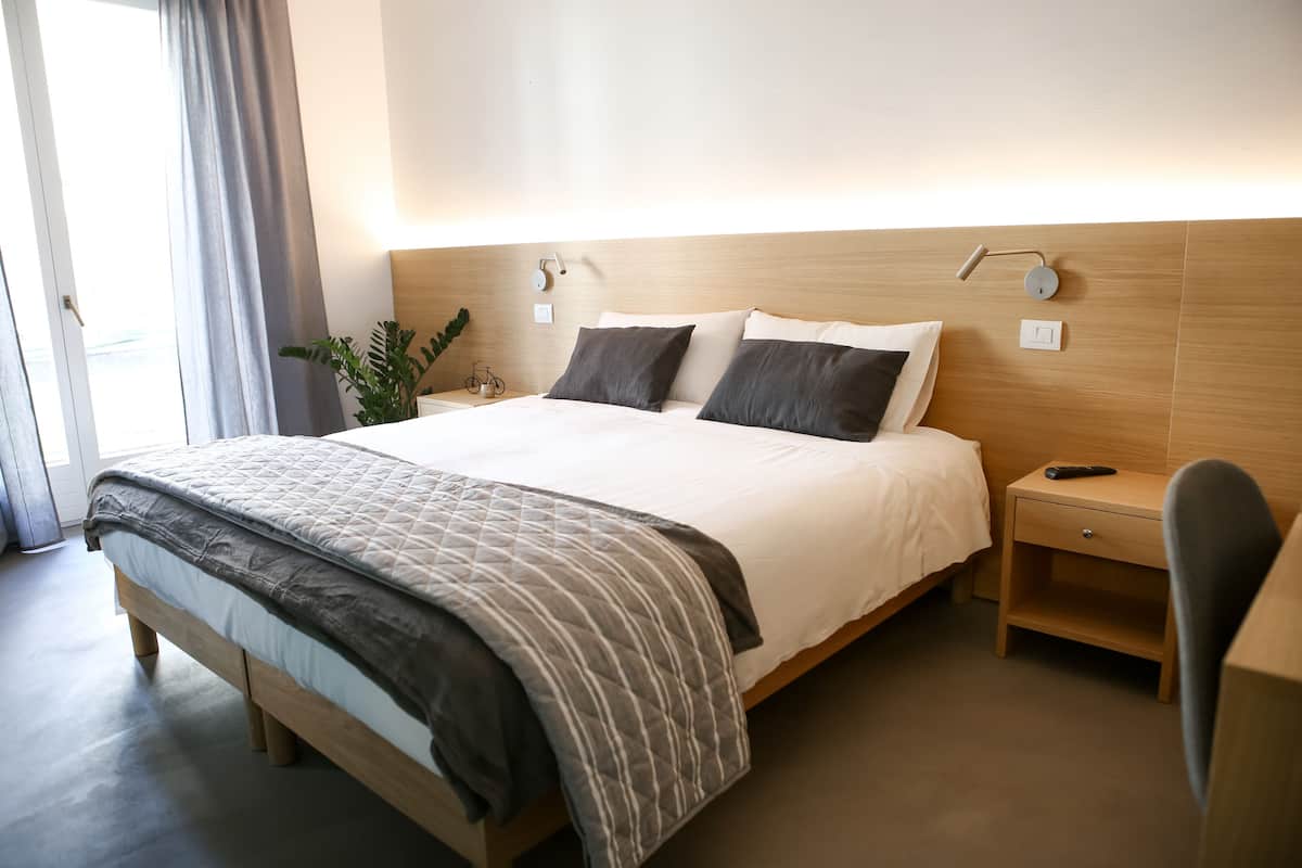 Une chambre d’hôtel moderne avec un grand lit, des tables de chevet, un bureau et une chaise.