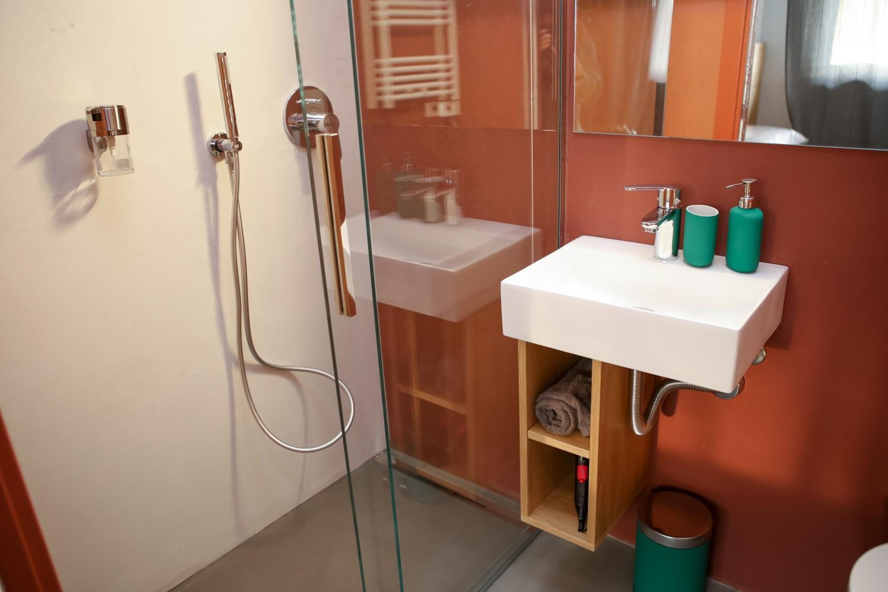 Une salle de bain moderne avec une douche à parois de verre, un lavabo blanc et un miroir au-dessus.