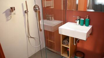Une salle de bain moderne avec une douche à parois de verre, un lavabo blanc et un miroir au-dessus.