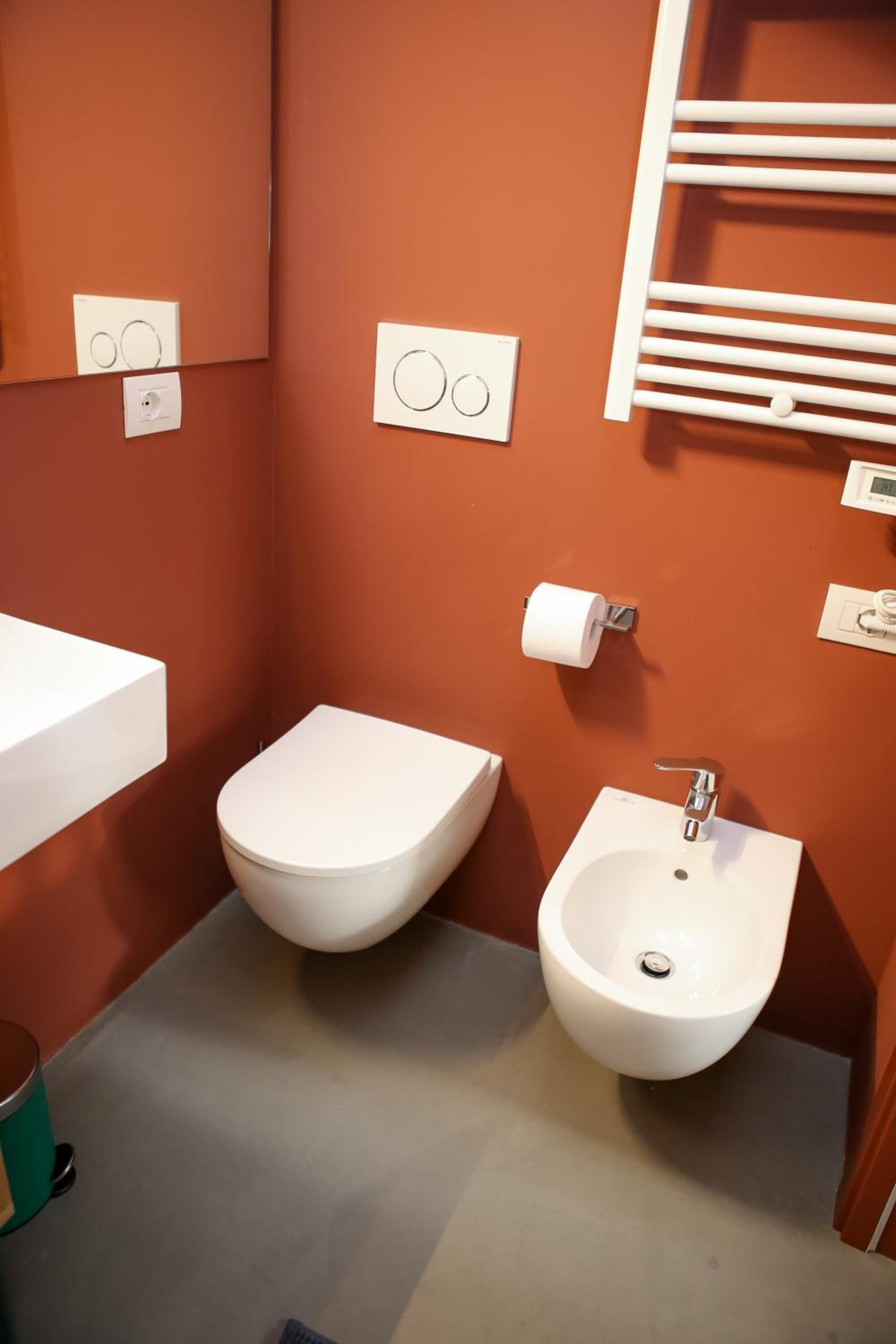A small bathroom with a toilet, bidet, and a white sink.