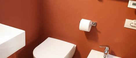 A small bathroom with a toilet, bidet, and a white sink.