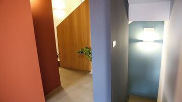 A hallway with a wooden partition, a potted plant, and a light fixture on the wall.