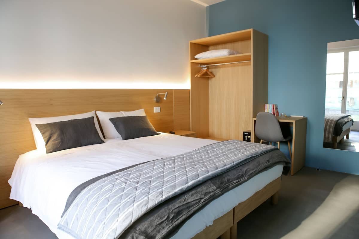 Une chambre d’hôtel bien aménagée, avec un lit, un bureau et une armoire.
