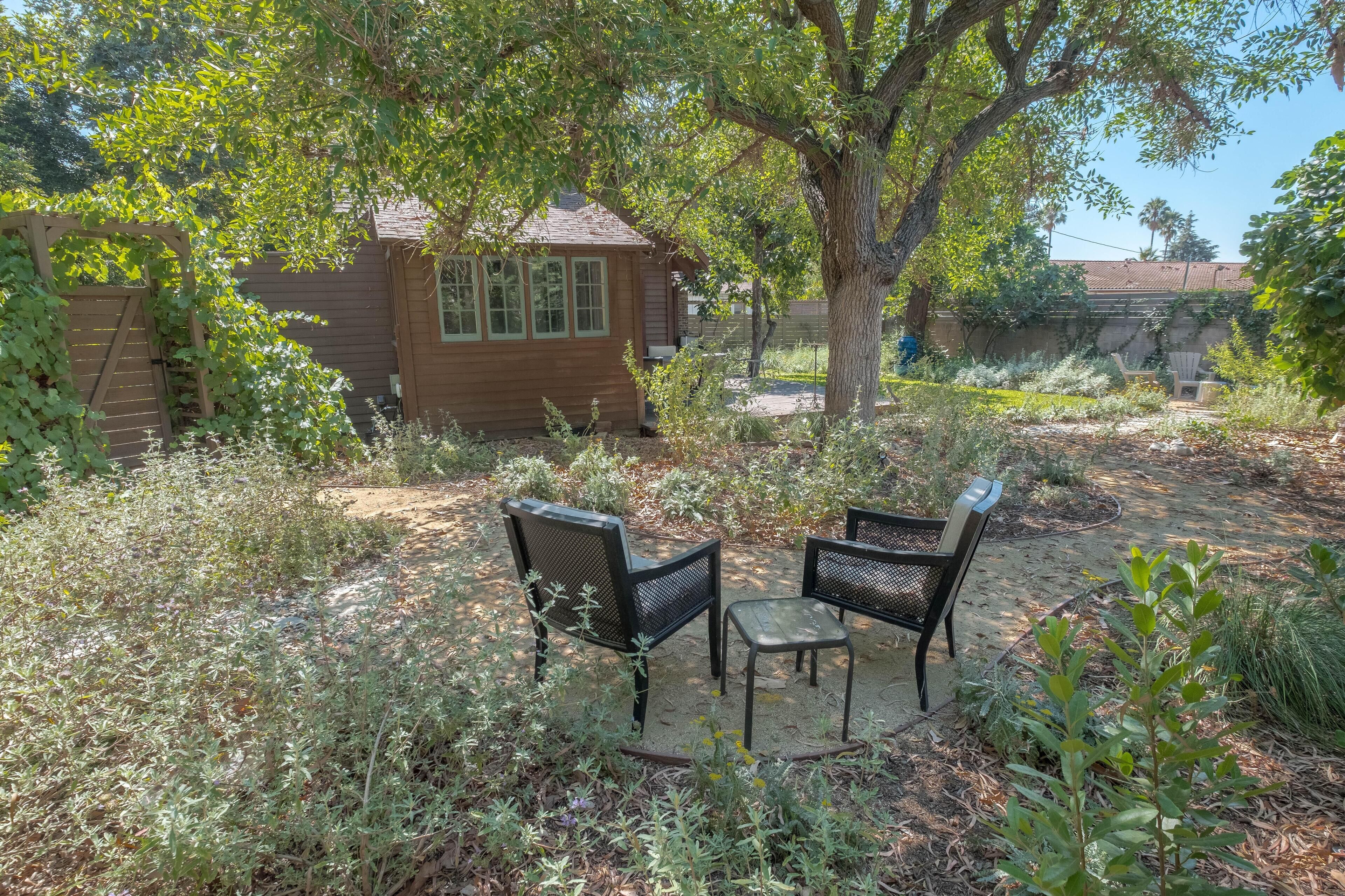 A rustic wooden cabin with a small porch and two metal chairs.