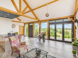 Habitació àmplia amb cuina, zona de menjador i grans portes corredisses de vidre que donen a una vista exterior panoràmica.