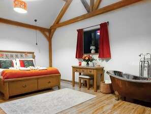 Um quarto com cama, escrivaninha, penteadeira e banheira.