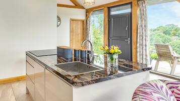 A kitchen with a marble countertop, a sink, and a wooden door leading to a balcony.