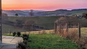 Een landelijk landschap met glooiende heuvels, een heldere lucht en een verre blik op een kleine nederzetting.