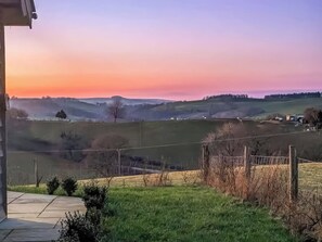 Paisaje rural con colinas onduladas, cielo despejado y una vista distante de un pequeño poblado.