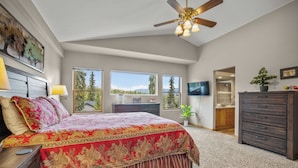A bedroom with a large bed, a ceiling fan, a TV, and a view of trees through the windows. - Quiet Townhouse Snuggled up to a Wooded Mountain View CS1 (Silverthorne)