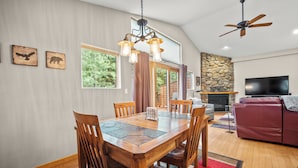 A dining area with a wooden table and chairs, a chandelier, and a stone fireplace. - Quiet Townhouse Snuggled up to a Wooded Mountain View CS1 (Silverthorne)