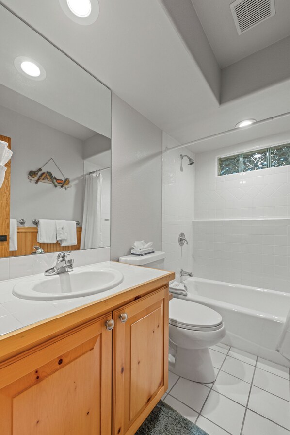 A modern bathroom with a wooden vanity, white sink, and a bathtub. - Luxurious Townhome Nestled in the Woods w/Large Deck (Silverthone)