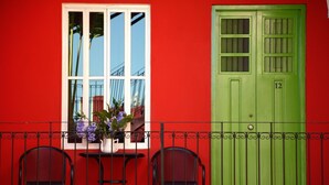 Un bâtiment rouge avec une porte verte et une fenêtre dotée d’un cadre blanc.