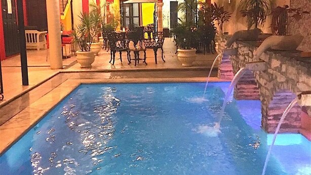 Une piscine intérieure avec un mur en pierre et un espace détente comprenant des tables et des chaises.