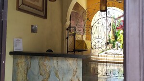Un comptoir d’accueil avec un plateau en marbre, une œuvre d’art encadrée au-dessus, et une enseigne indiquant « HÔTEL MEJORADA ».