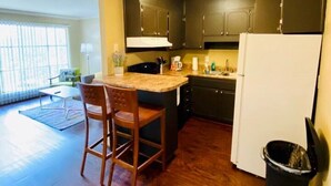 A compact kitchen with dark cabinets, a white refrigerator, and a wooden bar stool. - 1st Floor Highlands Hideaway (Spectacular Views) (Birmingham)