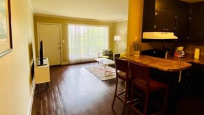 A spacious kitchen with dark wooden cabinets, a central island with bar stools, and a large window with blinds. - 1st Floor Highlands Hideaway (Spectacular Views) (Birmingham)