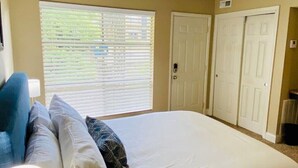 A bedroom with a bed, a nightstand, a lamp, a window with blinds, and a door. - 1st Floor Highlands Hideaway (Spectacular Views) (Birmingham)