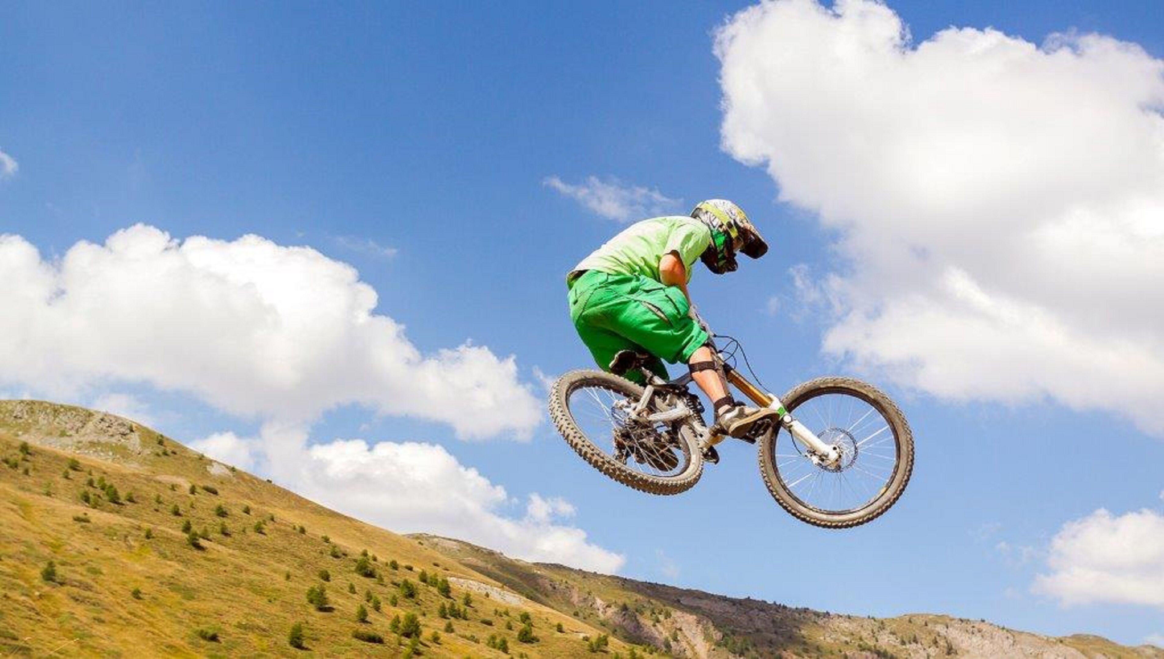 A person on a mountain bike performing a jump over a hill.