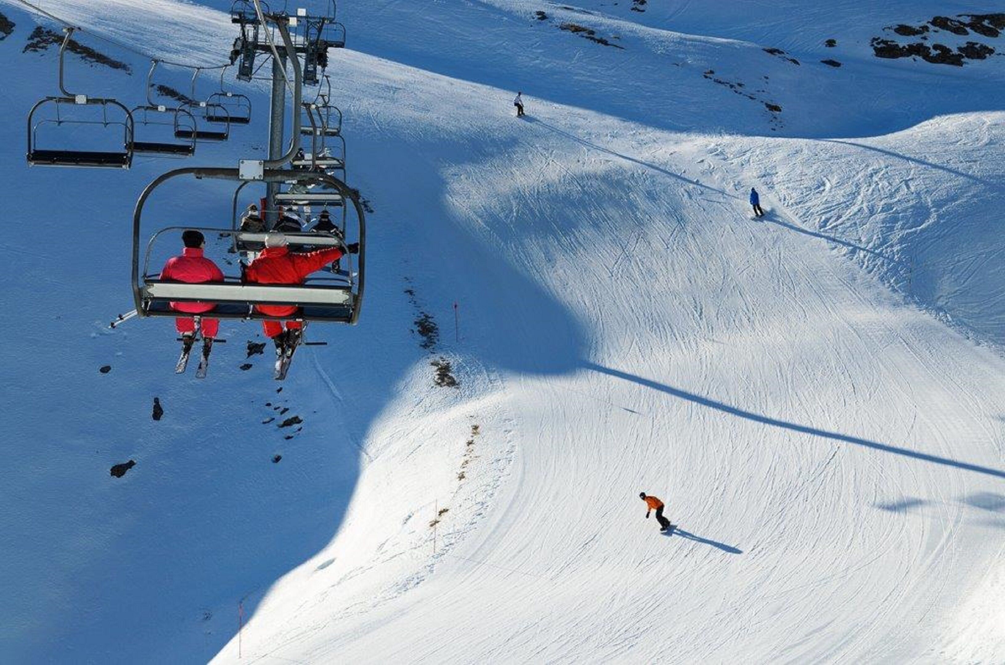 A ski lift with skiers in red jackets.