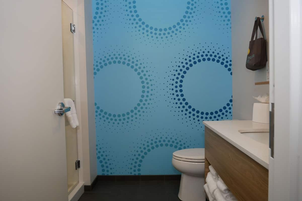 A bathroom with a toilet, a sink with a towel, and a wall with a blue dotted pattern.