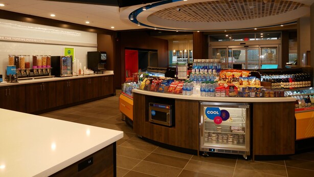A self-service beverage station with a refrigerated display and a variety of snacks. - Tru By Hilton Chambersburg, PA (Chambersburg)