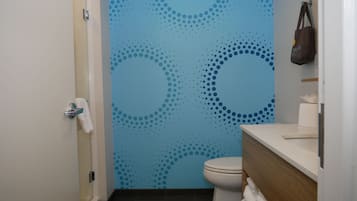 A bathroom with a blue wall featuring a dotted pattern, a white toilet, and a wooden vanity with a towel rack.