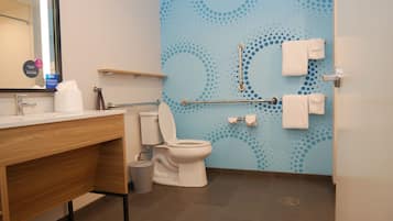 Une salle de bain moderne équipée de toilettes, d’un lavabo et de barres d’appui.