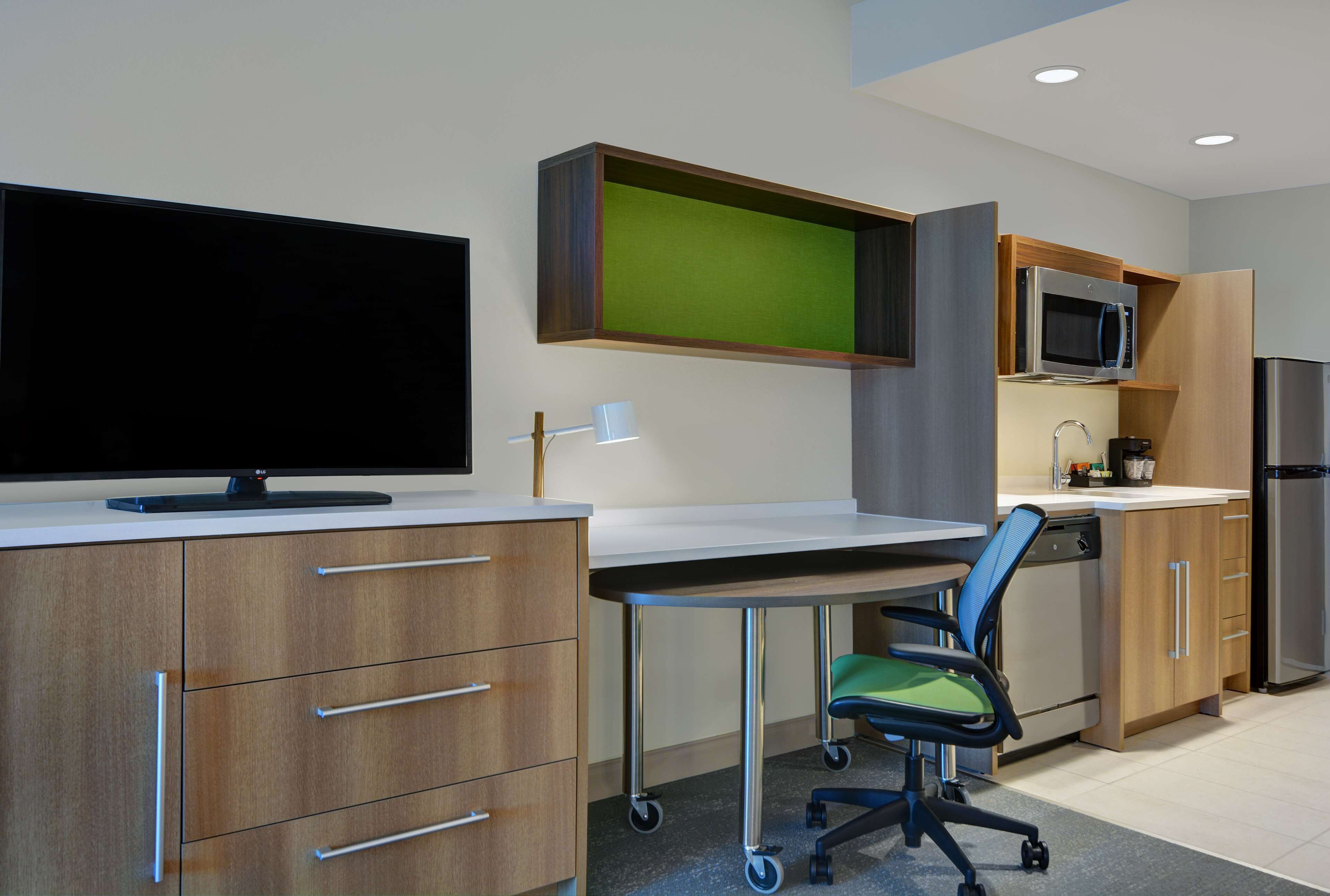 A modern kitchen with a flat-screen TV, a microwave, and a refrigerator.