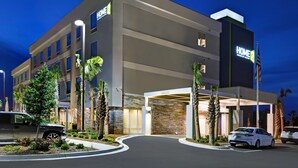 A modern hotel with a prominent "HOME 2" sign, featuring a well-lit entrance, landscaped gardens, and a parking area. - Home2 Suites by Hilton Panama City Beach, FL (Panama City Beach)