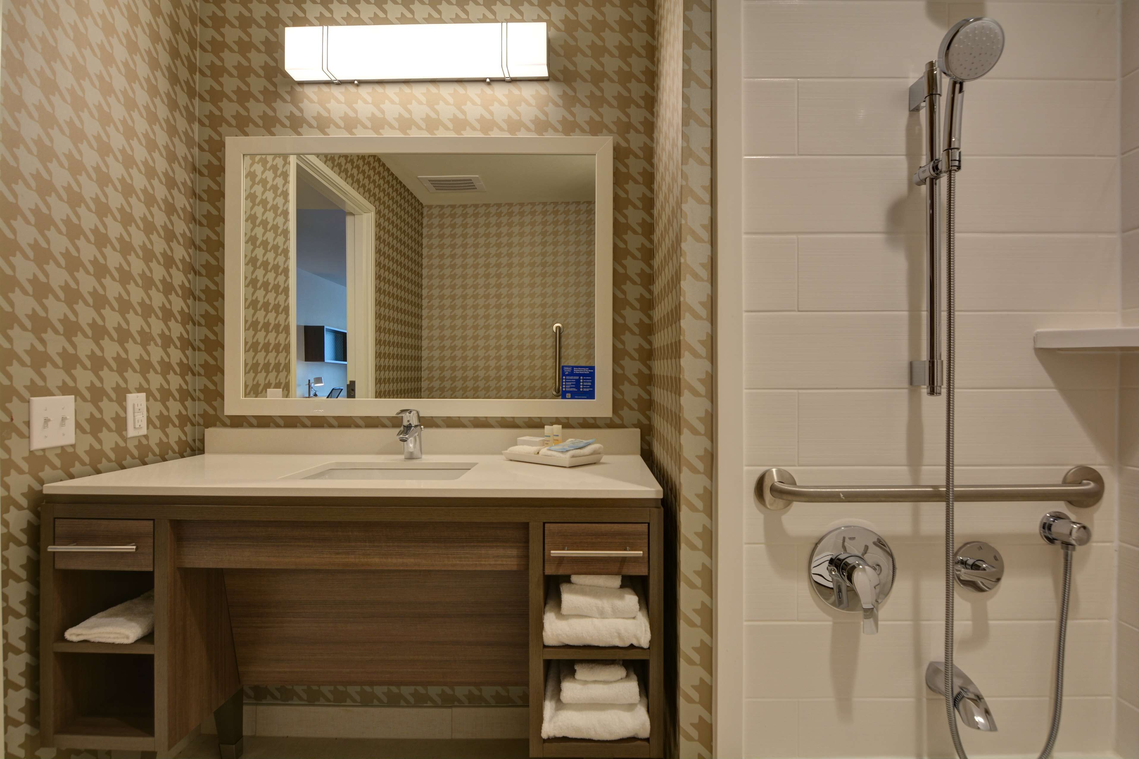 A bathroom with a sink, mirror, towel rack, and a shower with a handheld showerhead.