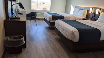 A hotel room with two beds, a desk, a chair, and a view of the outdoors.