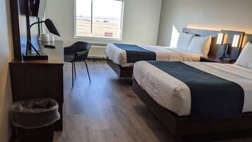 A hotel room with two beds, a desk, a chair, and a view of the outside.