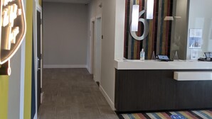 Ein Hotel-Rezeptionsbereich mit modernem Design, inklusive einer Rezeption, einem Ausgangsschild und einem farbenfrohen Streifen Teppich.
