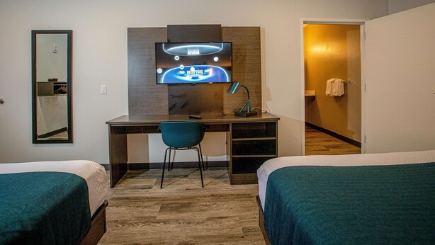 A hotel room with a bed, a desk with a computer, a chair, and a television mounted on the wall. - Motel 6 North Platte, NE - East (North Platte)