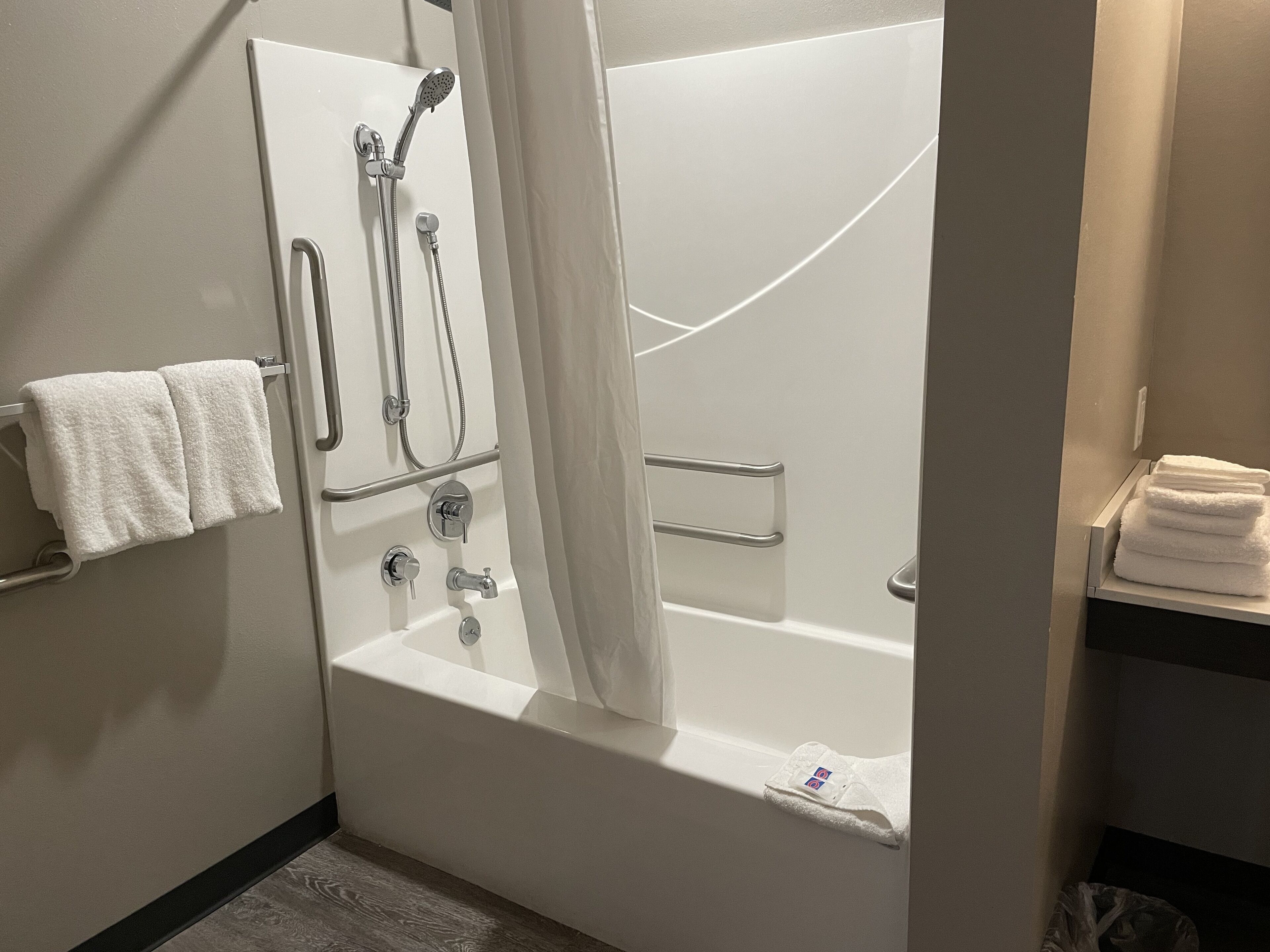 A modern bathroom with a walk-in shower, a bathtub, and a towel rack.