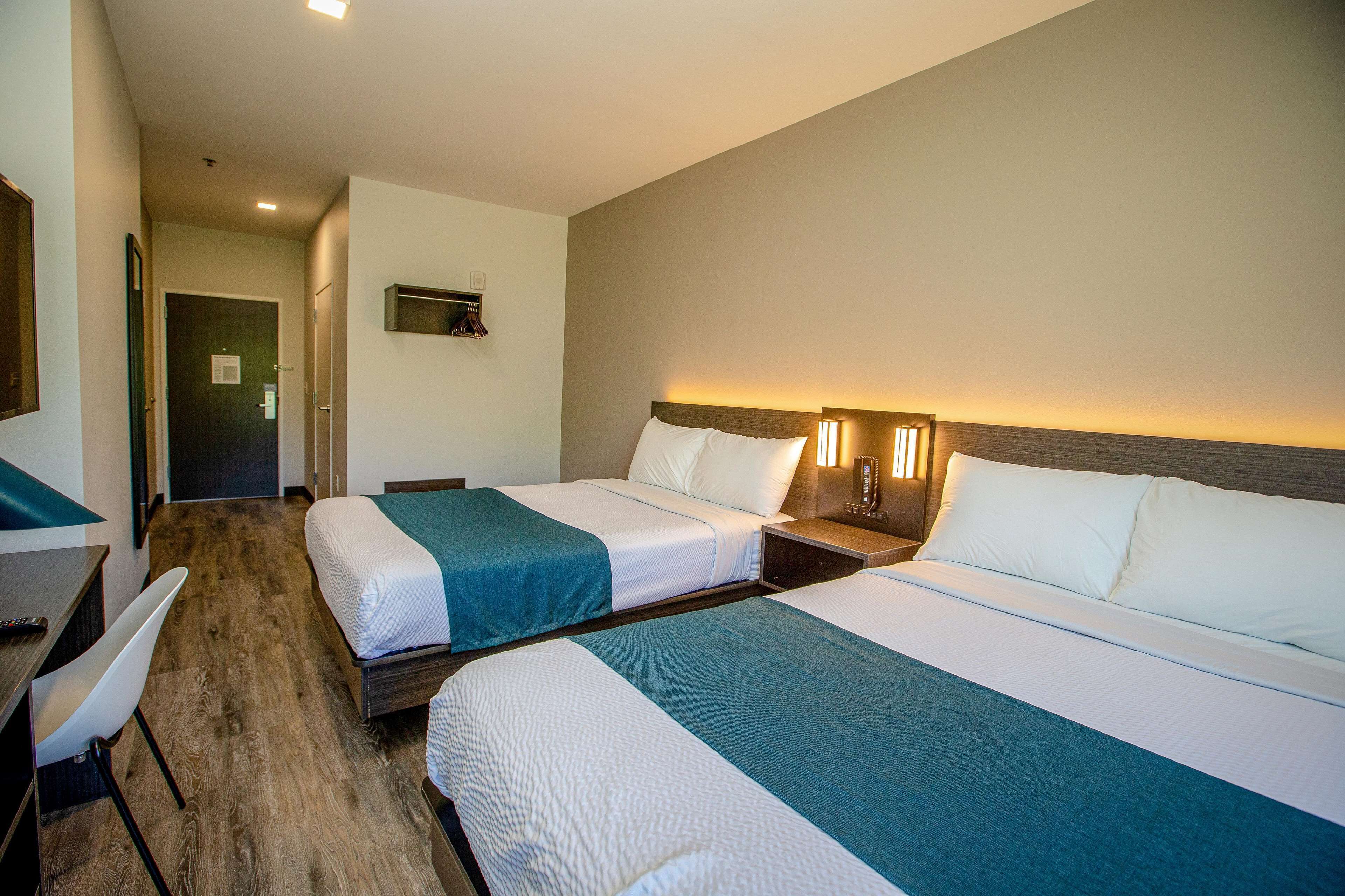 A hotel room with two beds, a desk, and a chair.