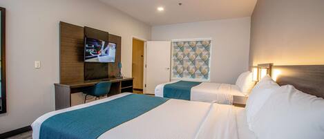 Habitación de hotel con dos camas, un escritorio, un televisor y una pared con diseño.