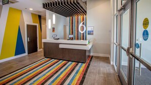 A reception area with a modern design, a striped carpet, and a glass door with a caution sign. - Motel 6 North Platte, NE - East (North Platte)