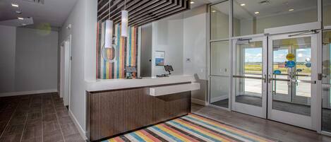 A reception area with a modern counter, a colorful striped carpet, and a glass door entrance.