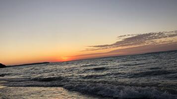 A beach at sunset with waves approaching the shore.
