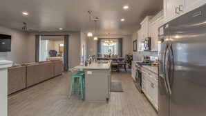 Una cocina moderna con una isla central, electrodomésticos de acero inoxidable y una zona de comedor con sofá y sillones.