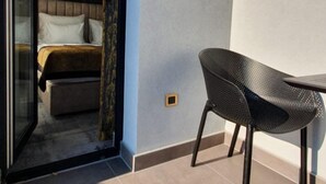 A modern room with a bed, a chair, and a view through an open door. - Hotel Pasha (Mostar)