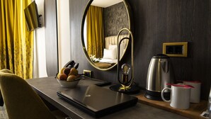 A hotel room with a bed, a mirror, a desk with a laptop, a bowl of fruit, a coffee maker, and a cup. - Hotel Pasha (Mostar)