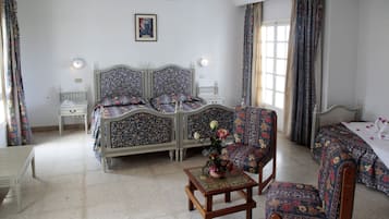 A room with a bed, a chair, a table, and a window.