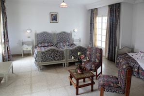 Una habitación con cama, una silla, una mesa y un ventanal.