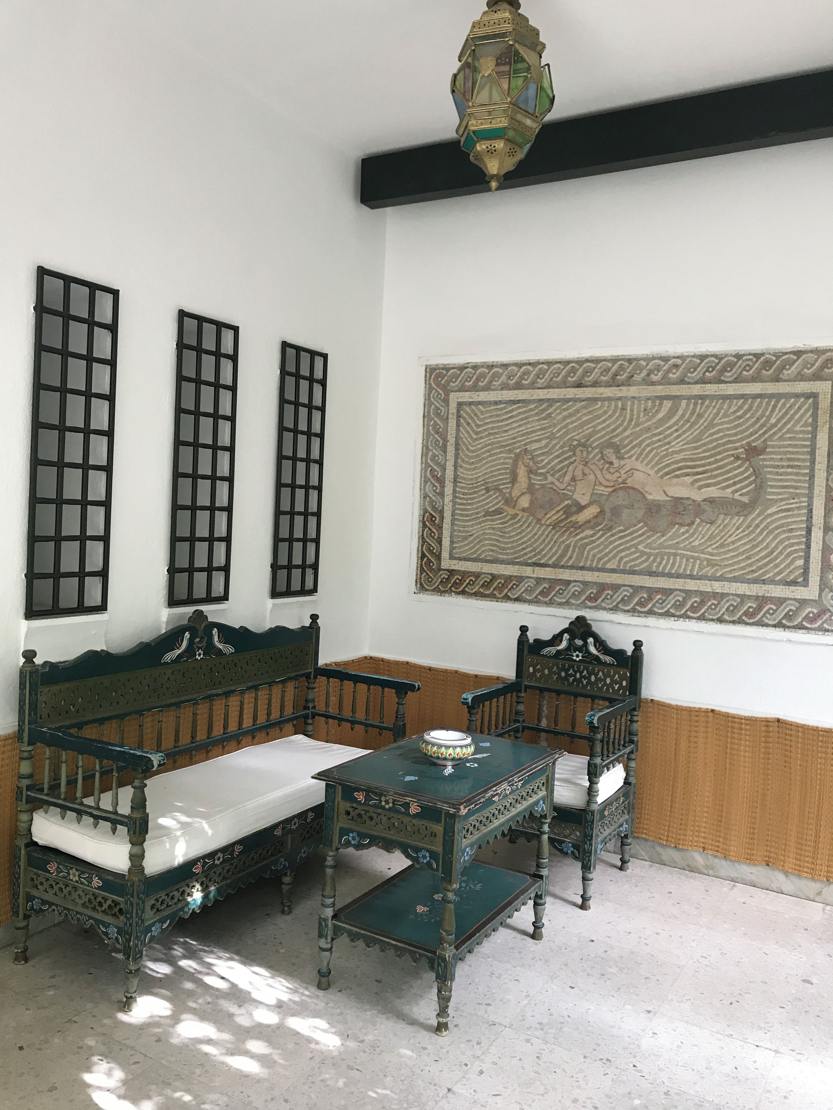 Une pièce comprenant un ensemble de meubles de salon de style traditionnel, une petite table et un luminaire décoratif suspendu.