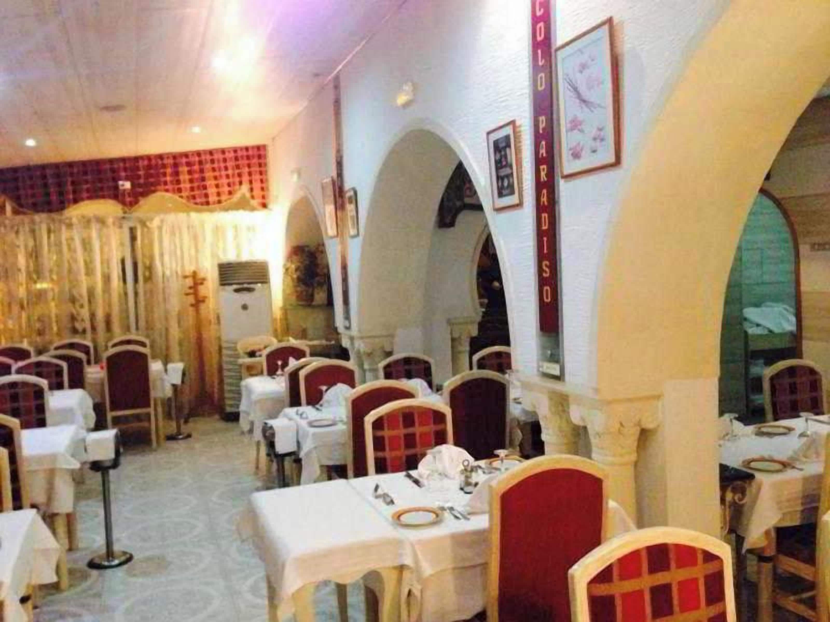 Un restaurante con varias mesas y sillas, una decoración en rojo y blanco y un diseño de interiores clásico.